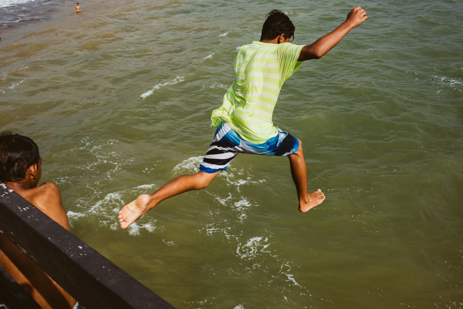 niños saltando del muelle al mar
