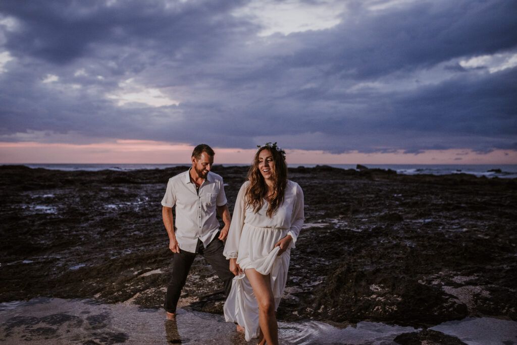 Pareja caminando junto al mar al atardecer durante su boda.
