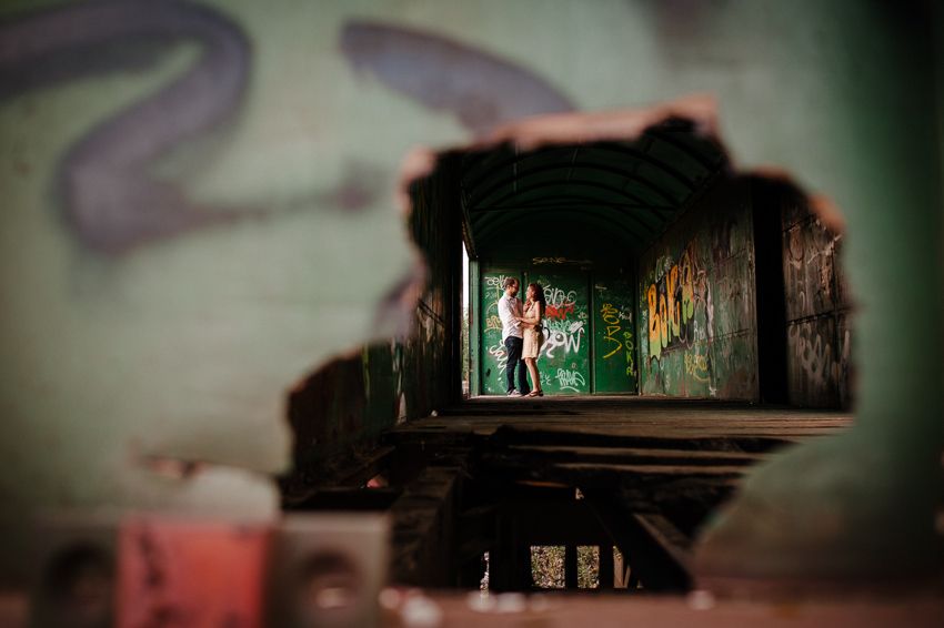 Pareja abrazada al fondo de un vagón de tren cubierto con grafitis