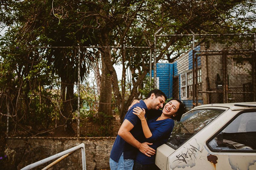Pareja riendo y abrazándose en un entorno urbano rodeado de árboles