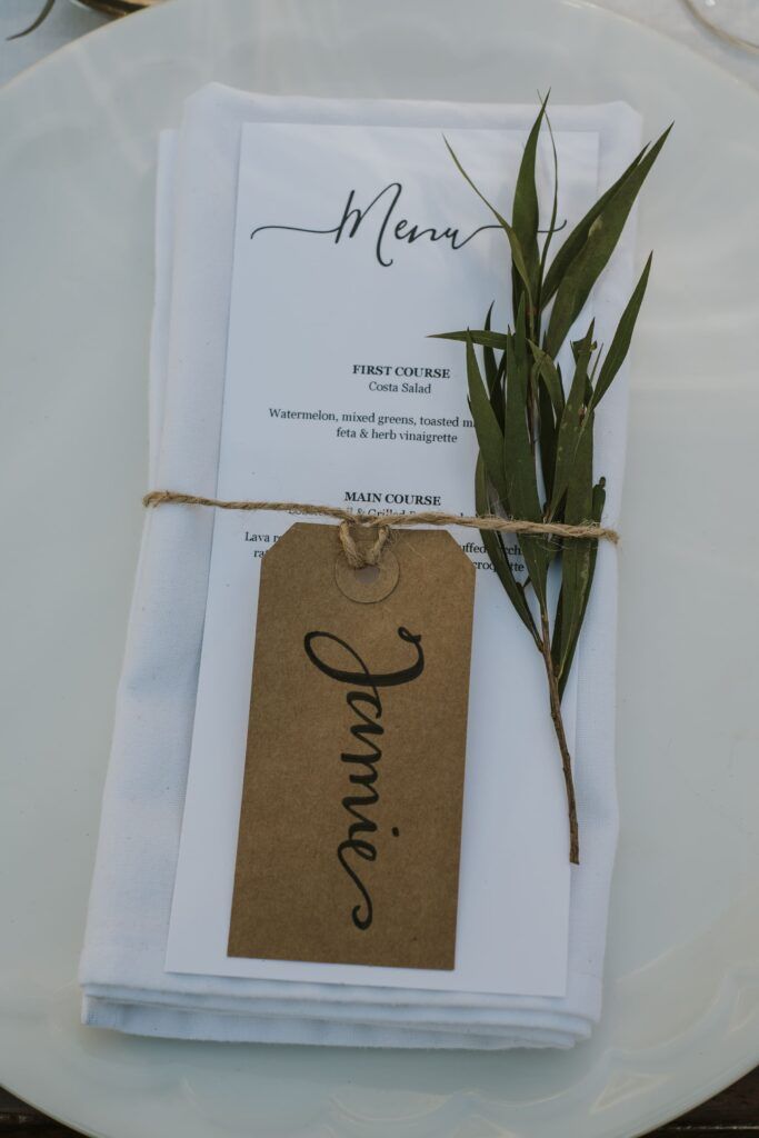 Minuta de boda con tarjeta de nombre y una rama verde