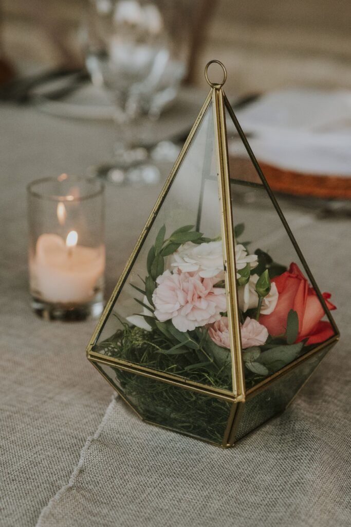Centro de mesa geométrico con flores rosadas y una vela